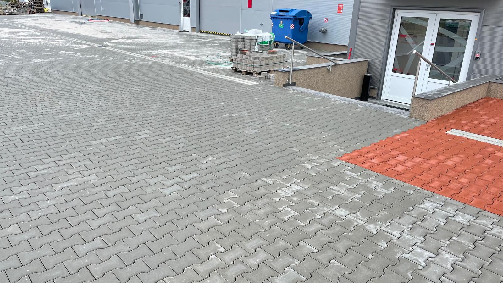 Detail dokončené šedé dlažby s červeným pruhem u vstupu do TKF